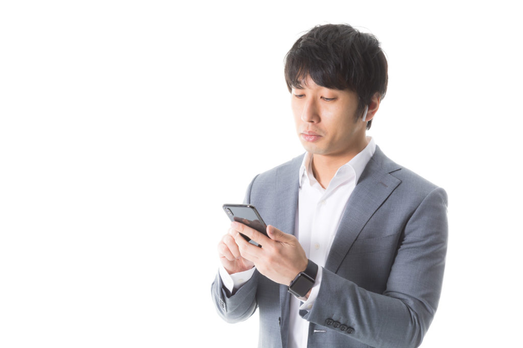 スマートフォンにデータ入力する男性の画像