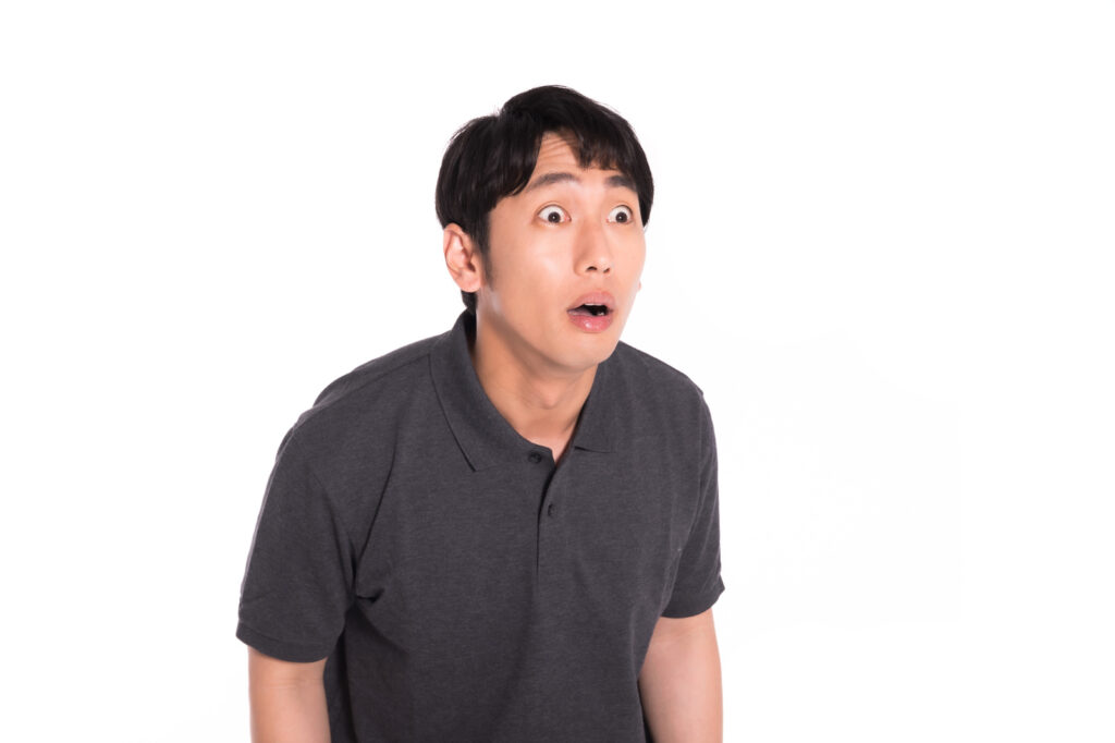 目を大きくしてびっくりする男性の画像