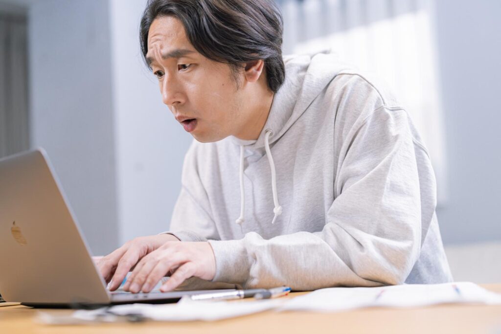 不安げにパソコンを覗く男性の画像