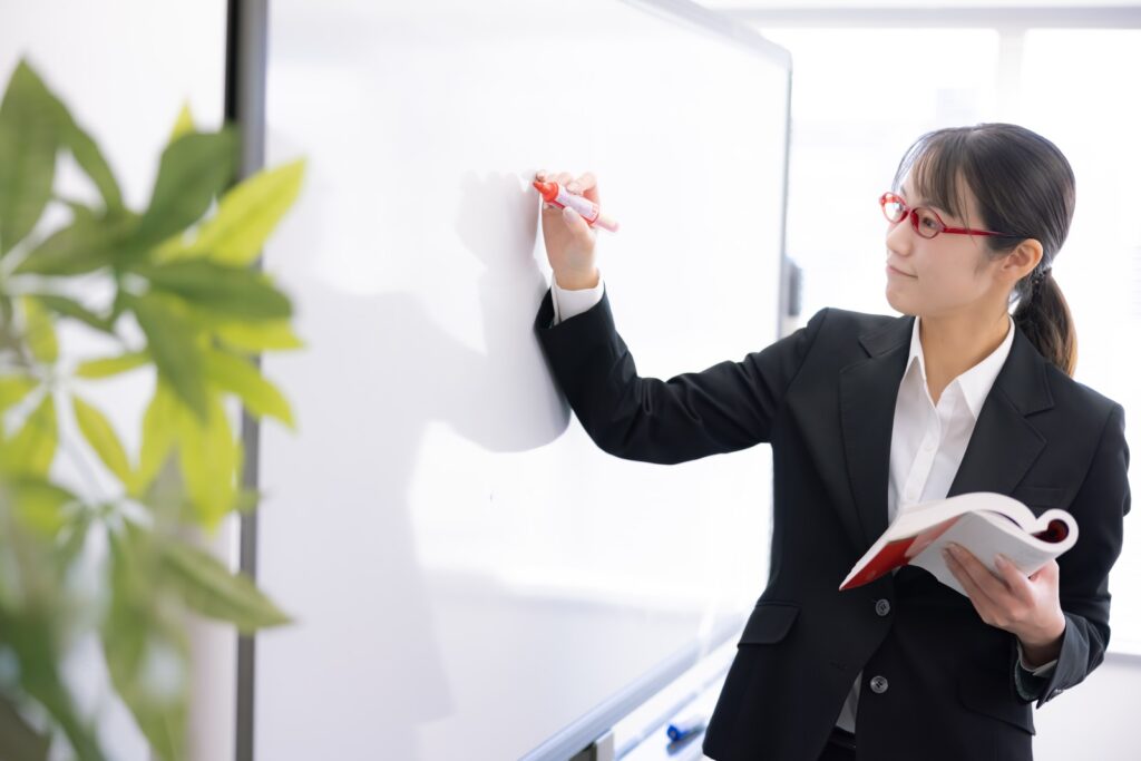 ホワイトボードにメモをする女性の画像