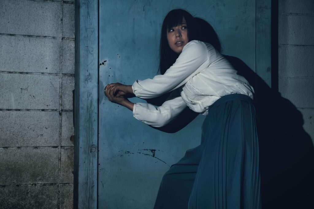 何者かに追われている女性が扉を開けようとしている画像
